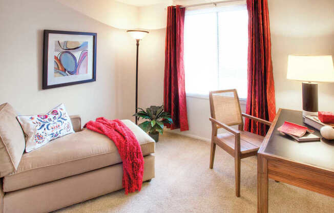 A living room with a beige couch, a chair, a table with a lamp, and a painting on the wall at Hummingbird Pointe & The Gardens, Parma