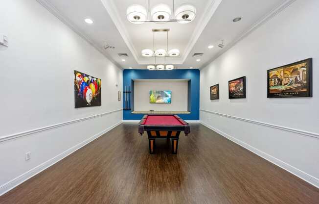 a game room with a pool table and paintings on the wall