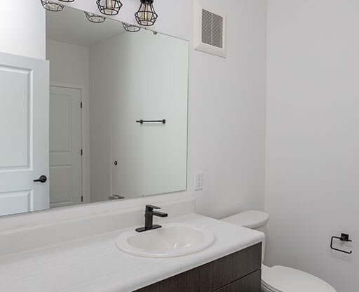 a bathroom with a sink toilet and mirror at The Landing at 1001 NP, Fargo, North Dakota 58102