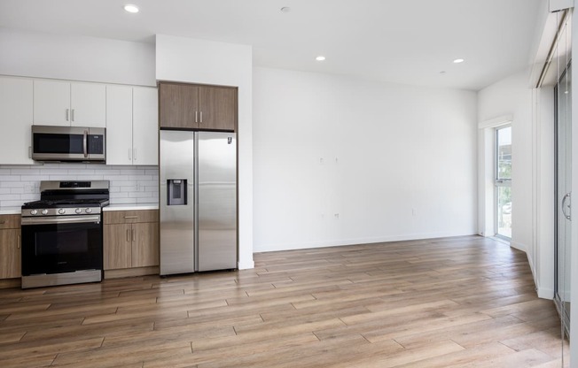 a kitchen with white walls and wooden floors and stainless steel appliances