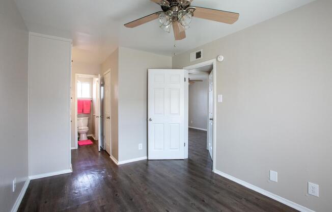 A room with a ceiling fan and wooden floors.