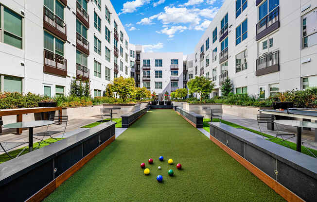 Bocce ball court surrounded by lush greenery and modern architecture, creating a vibrant community setting