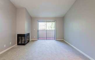 A spacious living room with a fireplace and a carpeted floor.