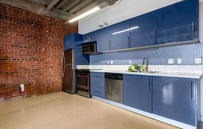 a kitchen with blue cabinets and a brick wall