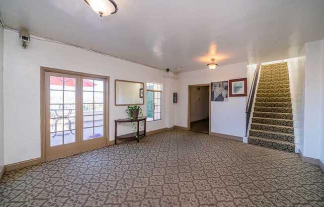 A room with a carpeted floor and a staircase on the right side.