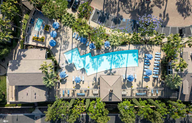 An aerial view of a pool surrounded by trees and buildings.
