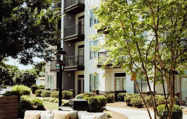 a patio with furniture and trees in front of an apartment building