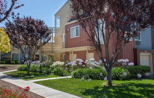 A row of houses with trees and flowers in front.