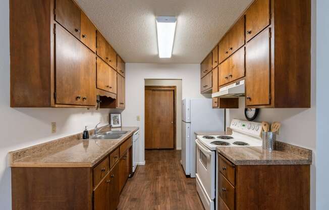 a kitchen with white appliances and wooden cabinets. Fargo, ND Betty Ann Apartments