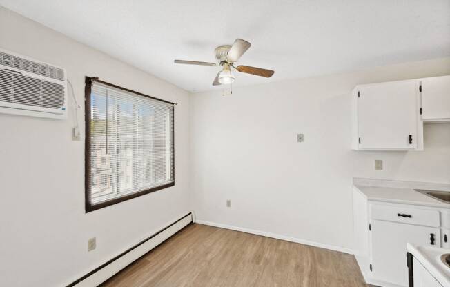 the living room and kitchen of an apartment with a ceiling fan and a window