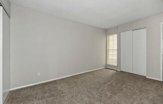 an empty living room with a closet and a window