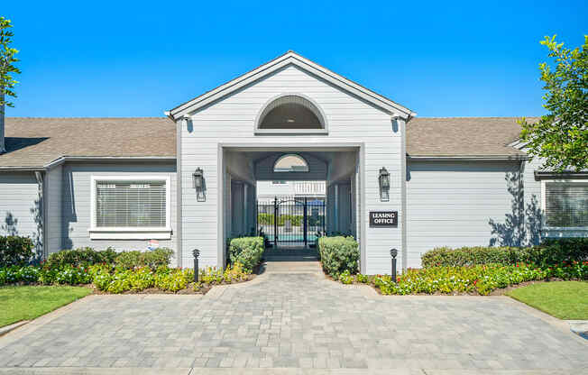 the front of a white house with a driveway and a gate