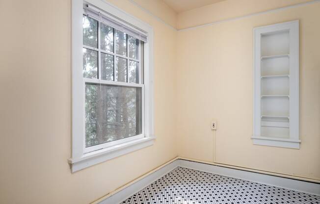 an empty room with two windows and a black and white tile floor