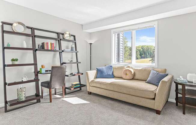 a living room with a couch and a desk and a window