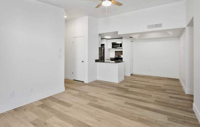 A room with a ceiling fan and wooden flooring.
