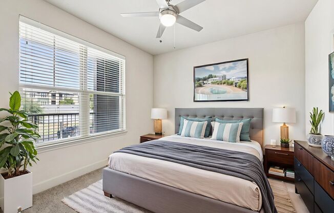 A bedroom with a large bed and a ceiling fan.