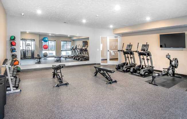 A gym with a variety of equipment including treadmills, weights, and exercise machines.