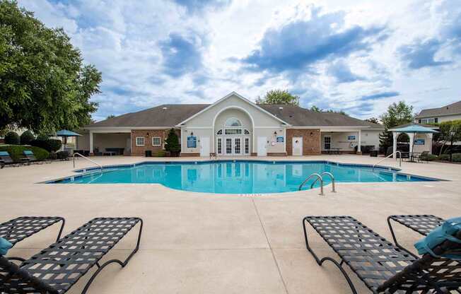 A pool with sun loungers in front of a building.