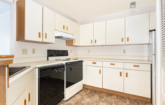 A kitchen with a black stove and dishwasher at Oak Shores Apartments in Oak Creek, WI