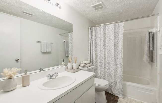 A white bathroom with a sink, toilet, and shower.