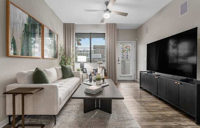 A living room with a white couch, a coffee table, and a flat screen TV.