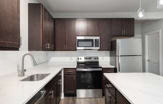 A modern kitchen with dark brown cabinets and stainless steel appliances.