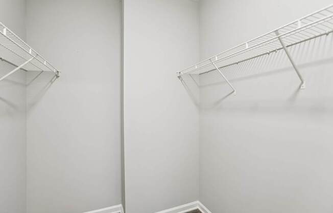 Two empty wire shelves in a white room.