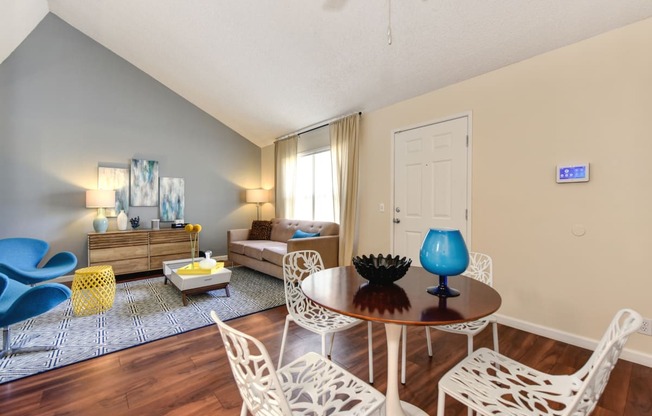 Living Room with View of Kitchen with Hardwood Inspired Floor, White Sofa, Rug and Blue Chairs