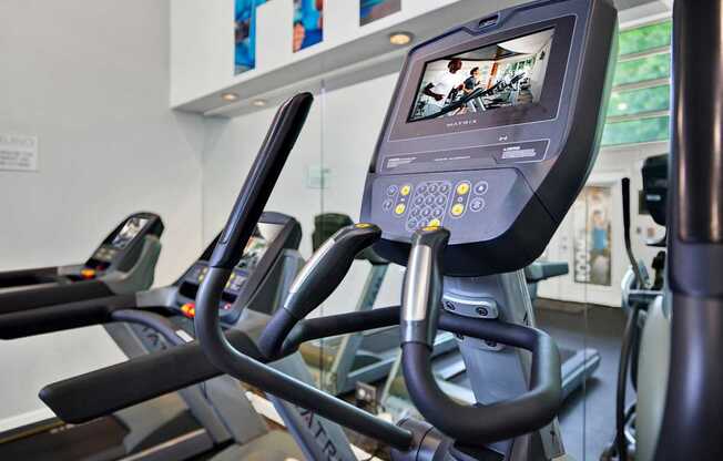 A row of treadmills in a gym with a monitor on the front.