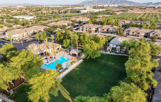 A bird's eye view of a neighborhood with a swimming pool and green lawns.