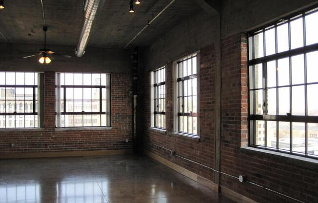 an empty room with large windows and a ceiling fan