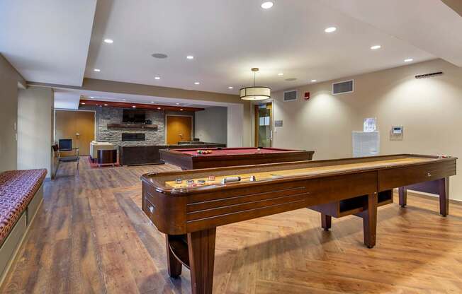 A pool table is in the middle of a room with wood floors.