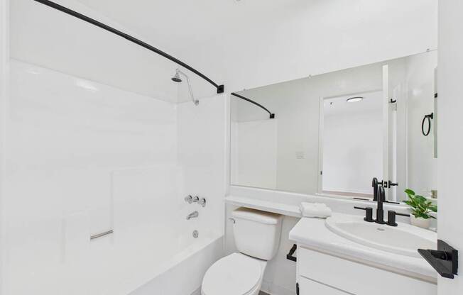 A white bathroom with a toilet, sink, and shower.