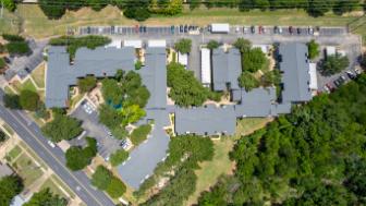 A large building complex surrounded by trees and a parking lot.