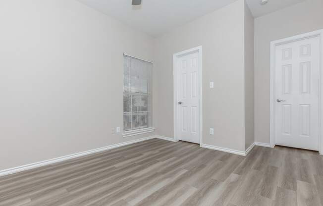a bedroom with hardwood flooring and two doors