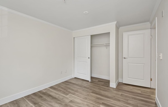 a bedroom with hardwood floors and white walls