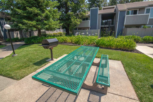 BBQ and Picnic table and benches in front of an apartment building