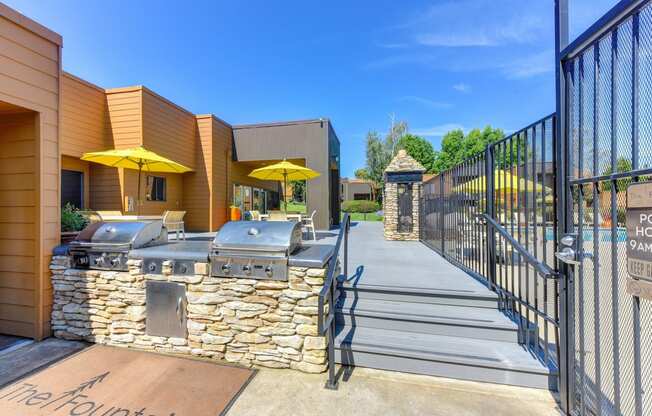 BBQ Area with Yellow Umbrellas, Grills, Gates with View of Pool