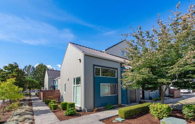 a gray and blue house with trees and a sidewalk