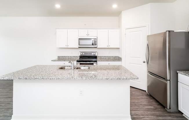a kitchen with white cabinets, granite countertops and stainless steel appliances