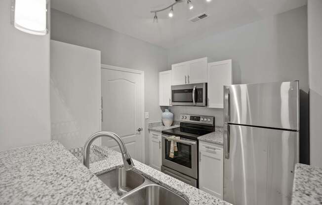 A kitchen with a sink, stove, and refrigerator.