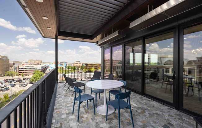 A balcony with a table and chairs overlooking a parking lot.