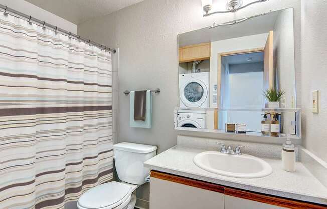 A bathroom with a toilet, sink, and mirror.