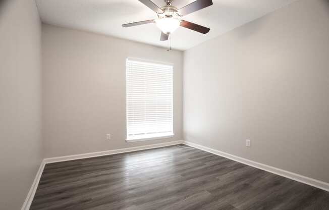 an empty living room with a ceiling fan and a window