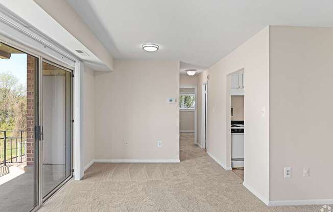 A spacious living room with a sliding glass door leading to a balcony.
