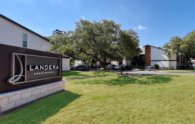 a grassy area in front of a building with a sign that says landera apartments