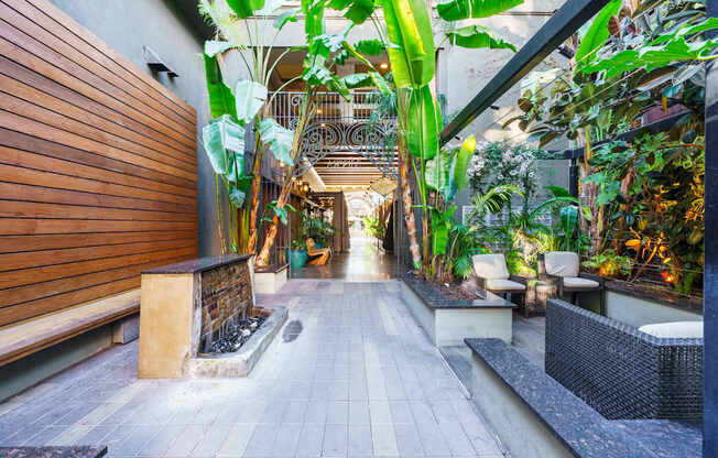 A long hallway with a staircase and plants on both sides.