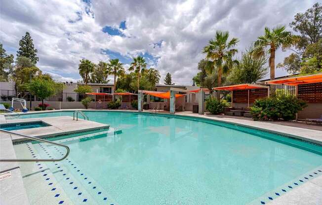 A large swimming pool with a diving board and a cloudy sky.
