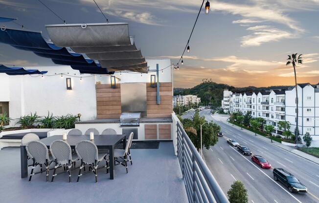 Rooftop lounge with outdoor dining, grilling area, and sunset views over Sherman Oaks.