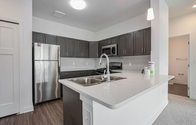 a kitchen with a large island and a stainless steel refrigerator at Meadowbrooke Apartment Homes, Grand Rapids, MI